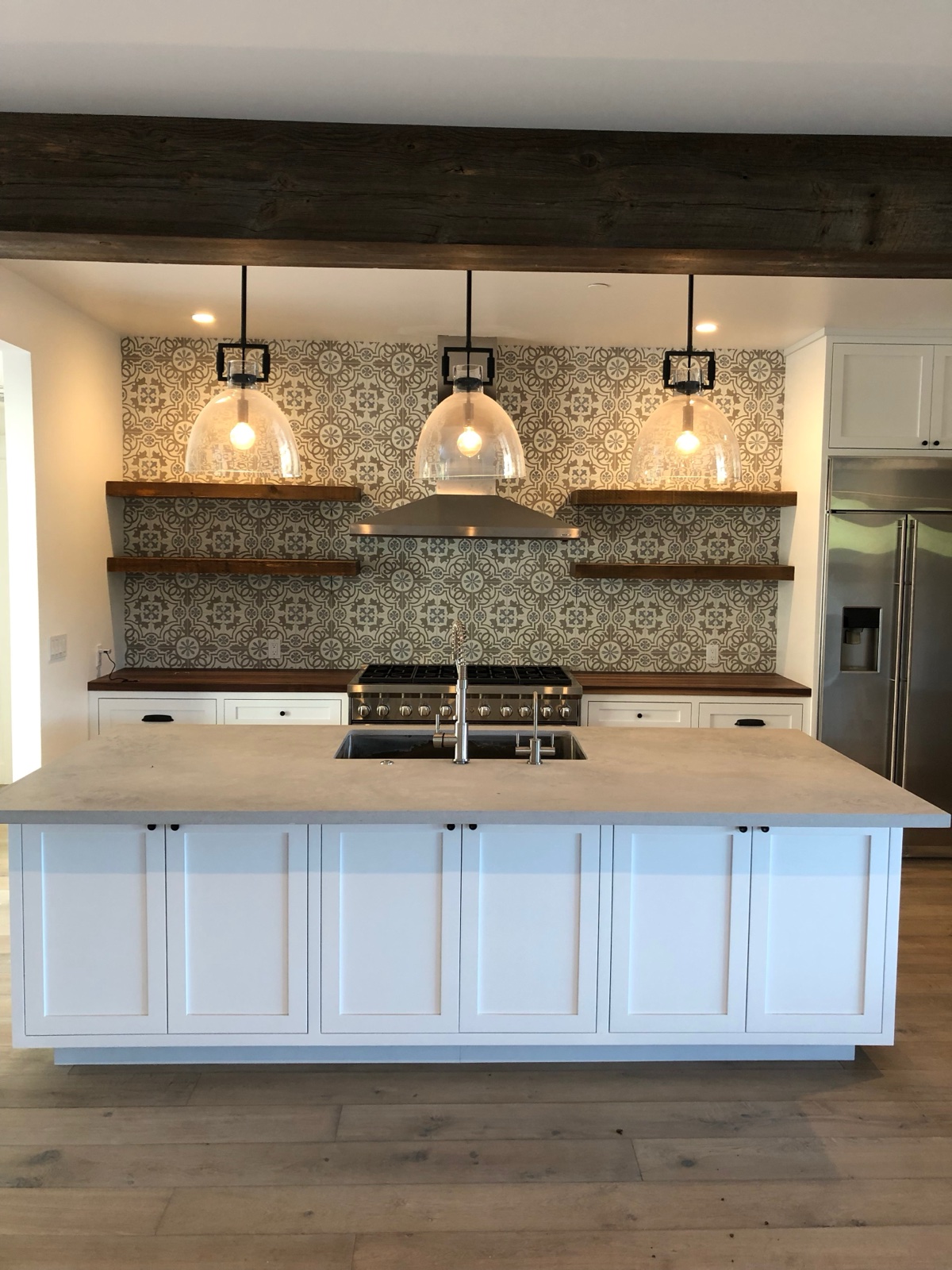 Kitchen remodel with patterned tile backsplash, open shelving, and professional range