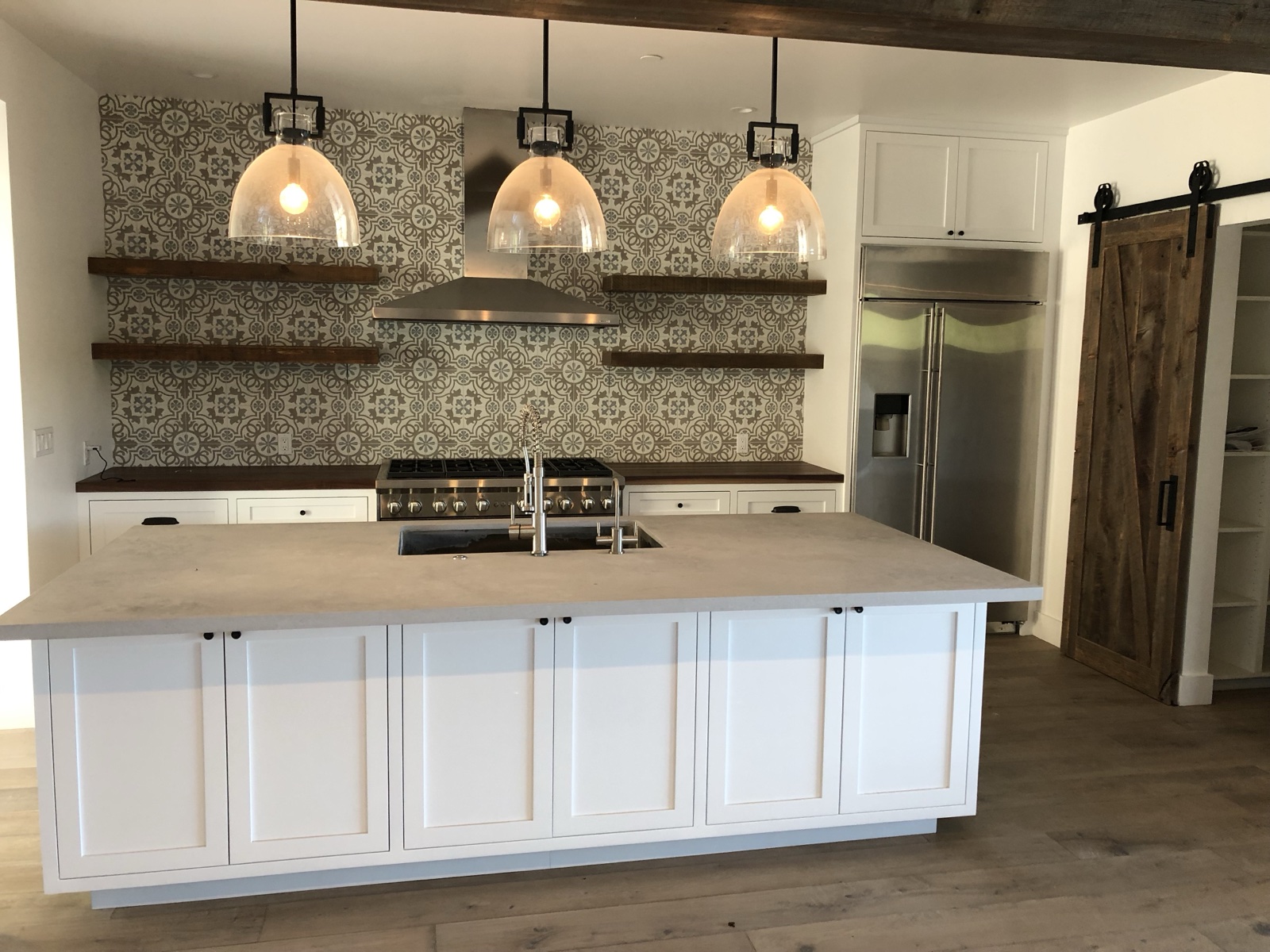 Kitchen renovation with large island, pendant lights, and reclaimed wood beam ceiling