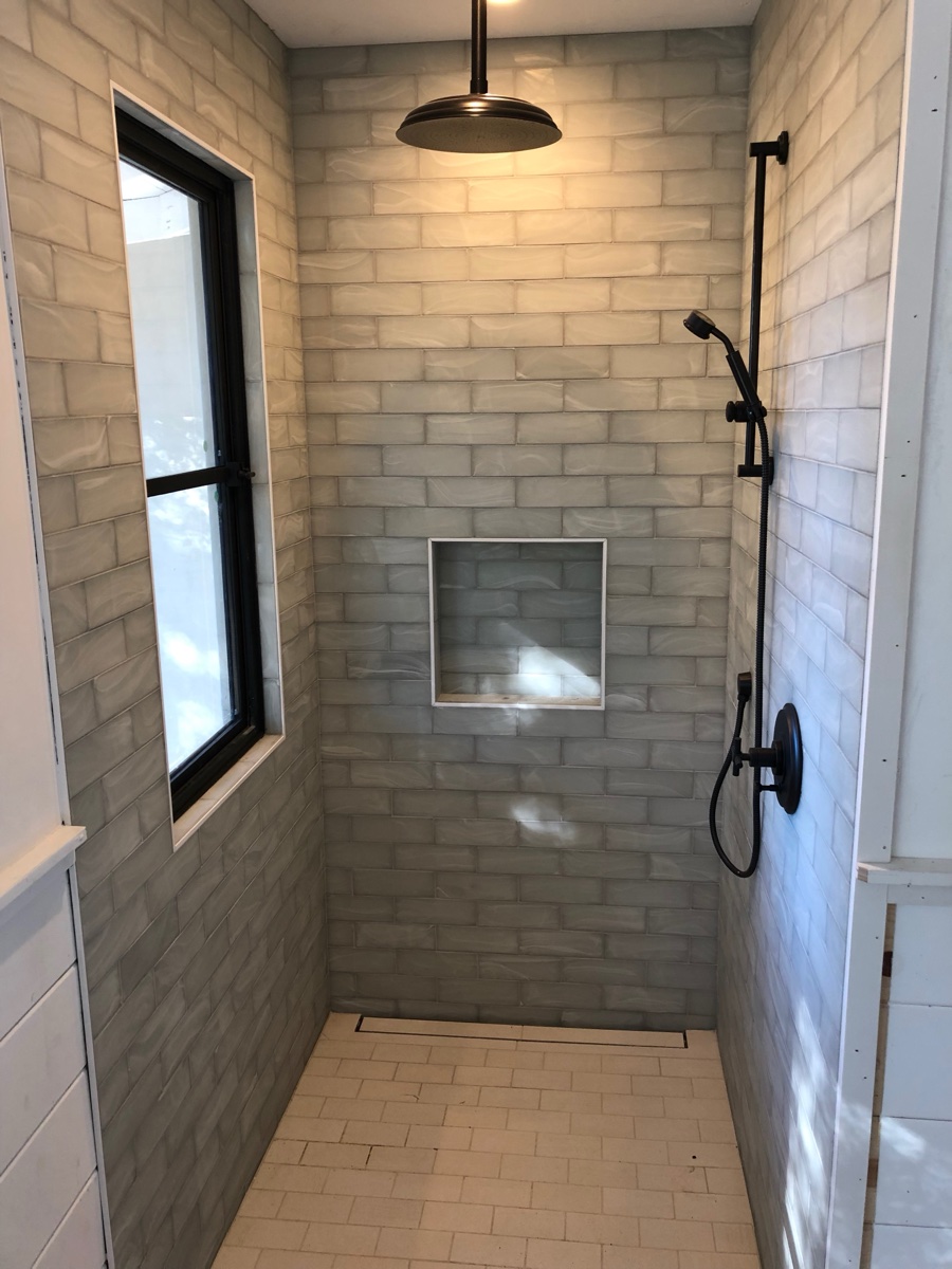 Custom walk-in shower with handcrafted tile and matte black rain head